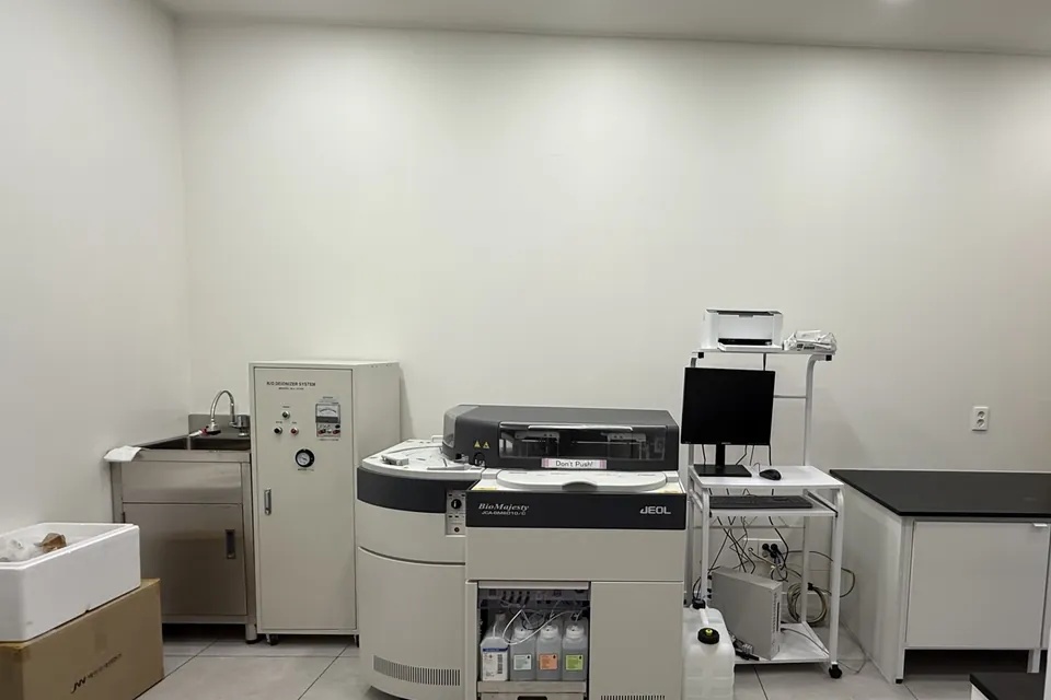서울 소재 외과의원 검사실 가운데에 설치된 JEOL JCA-BM6010/C 생화학분석기와 옆의 제어용 컴퓨터 받침대. 왼쪽 벽에 개수대와 정제수 장치가 있습니다.